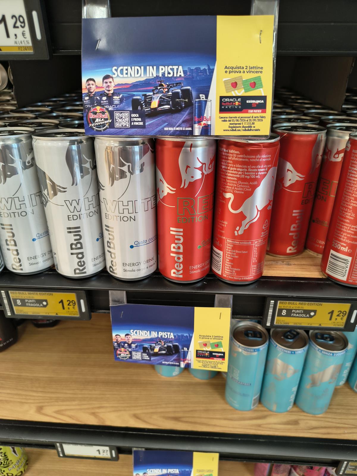Cartello del concorso Red Bull All Terrain 2026 sullo scaffale Esselunga con lattine Red Bull